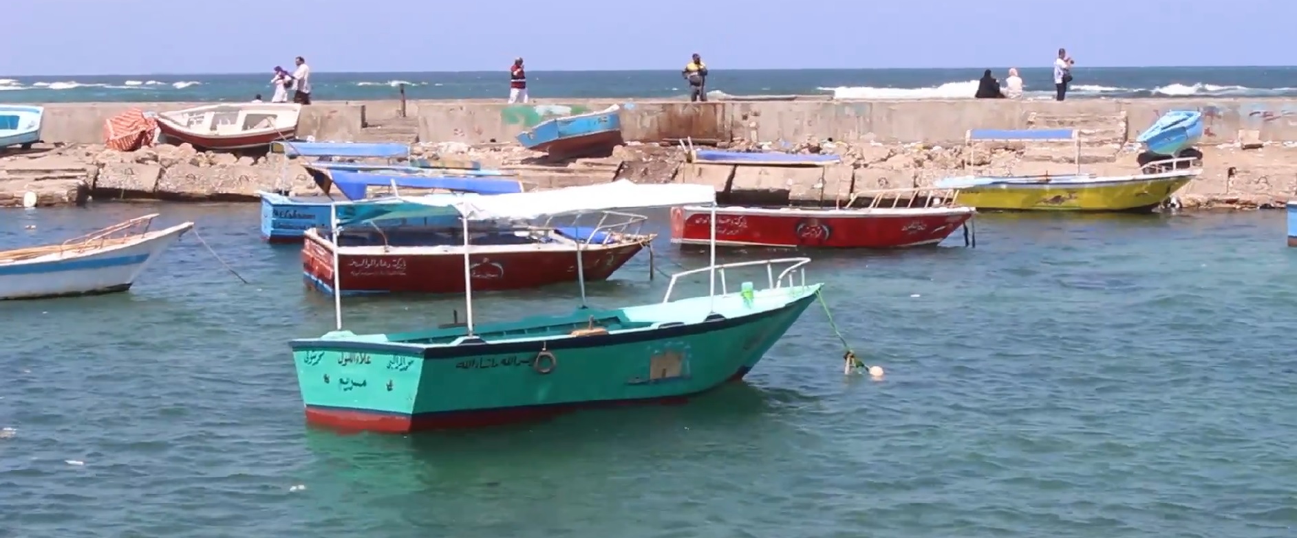 Traditionelle bunte Fischerboote im Hafen von Alexandria in Ägypten an einer Steinmauer