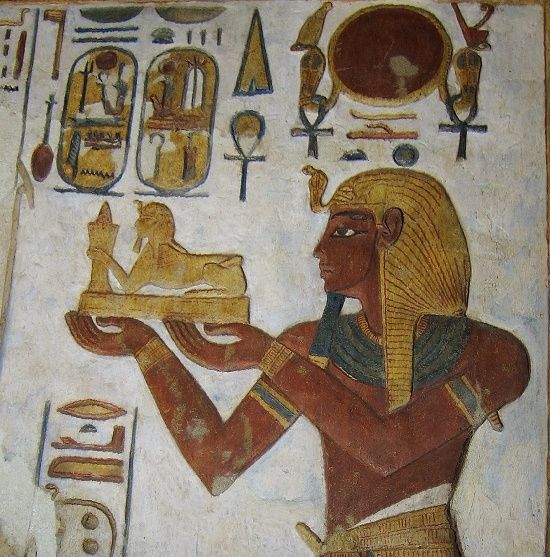 Altägyptische Wandmalerei mit einer Figur, die eine Sphinx unter Hieroglyphen hält