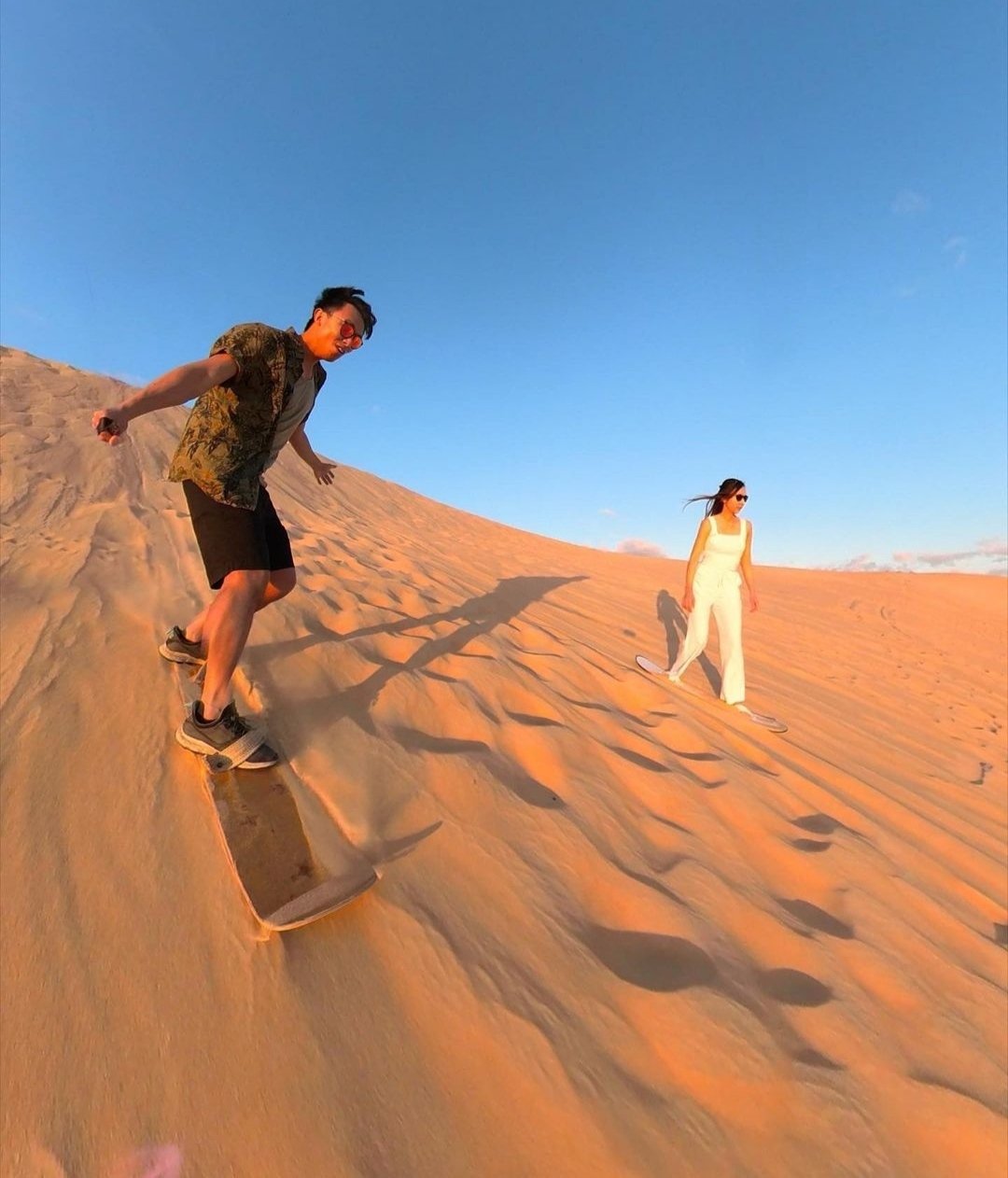Ein Paar beim Sandboarding in der Wüste von Ägypten