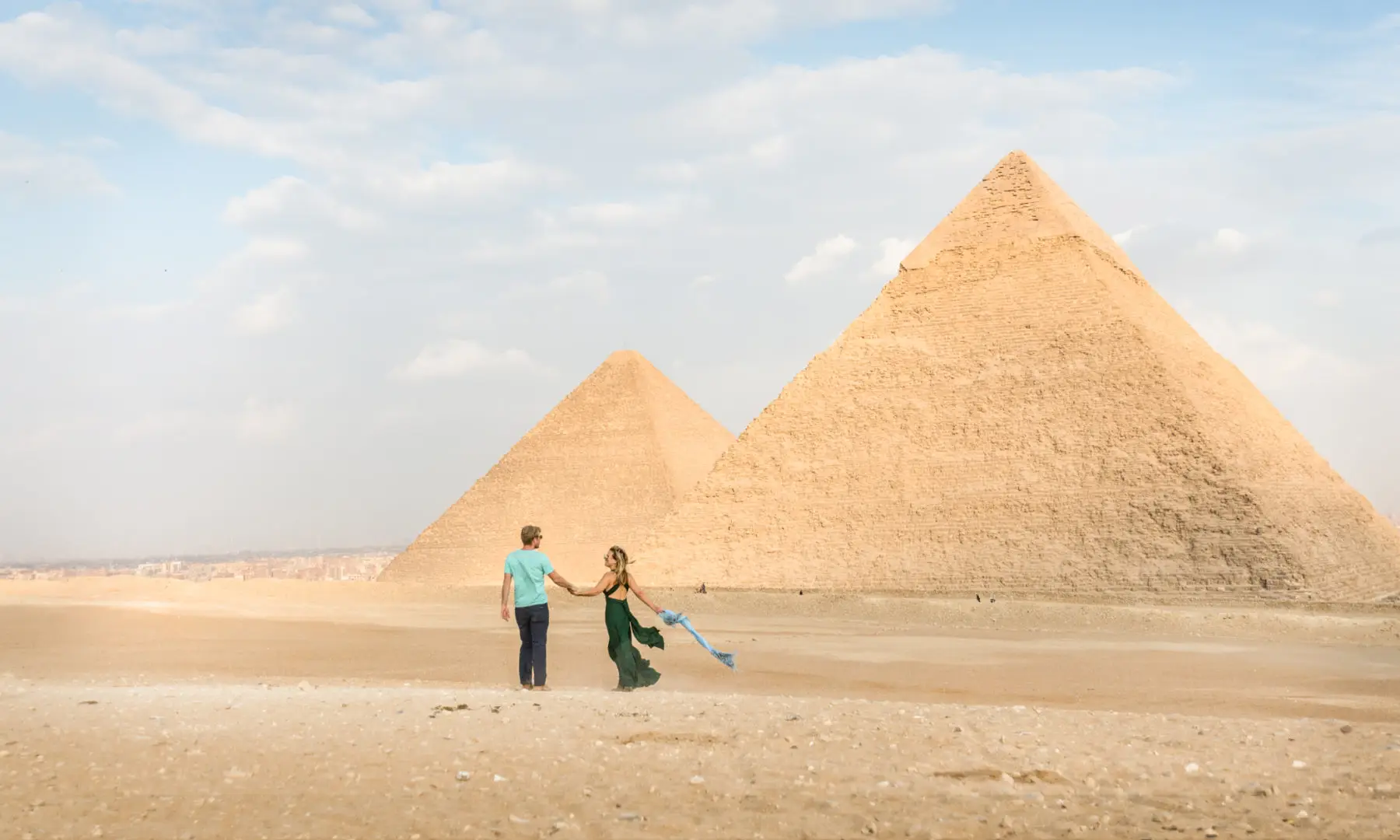 Romantisches Paar laeuft Hand in Hand bei den Pyramiden von Gizeh
