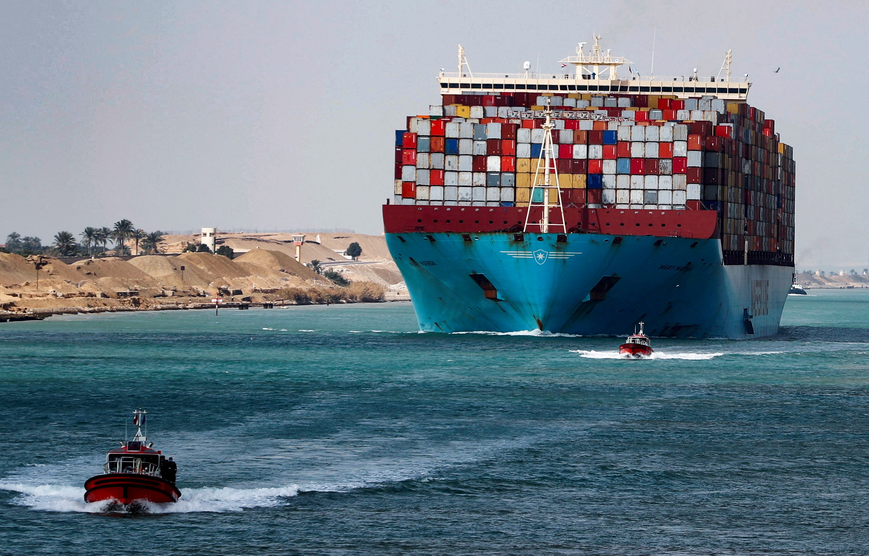 Gran buque portacontenedores en el Canal de Suez con remolcadores