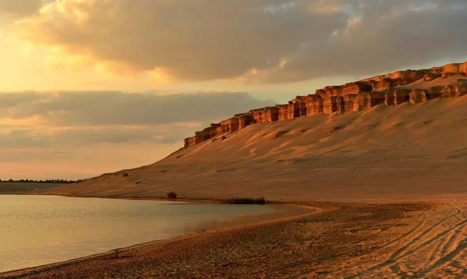 Wadi-El-Rayan-Tour: Blick auf den See und die Felsformationen im warmen Licht des Sonnenuntergangs.