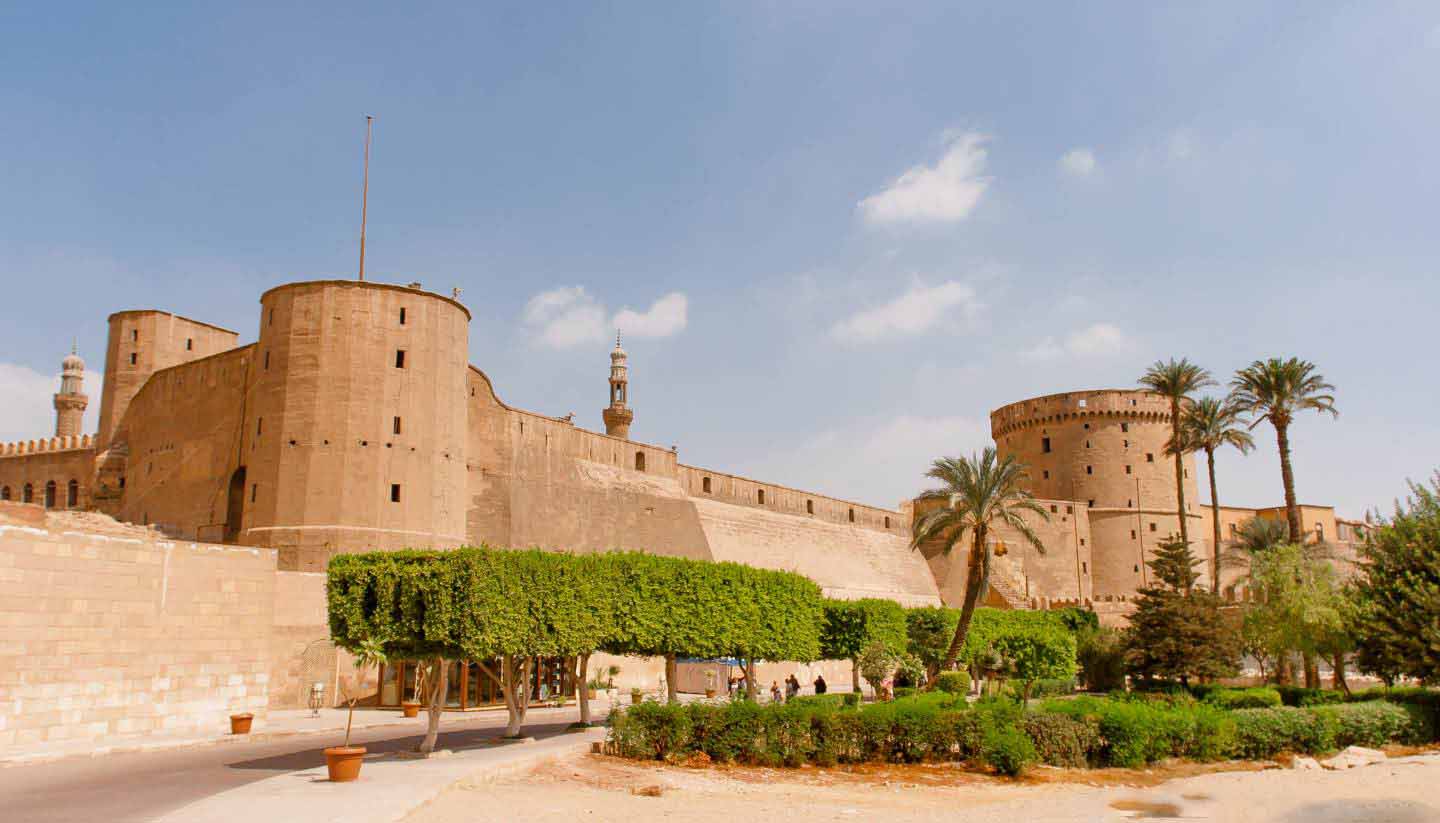 Remparts et tours en pierre près de jardins et de palmiers