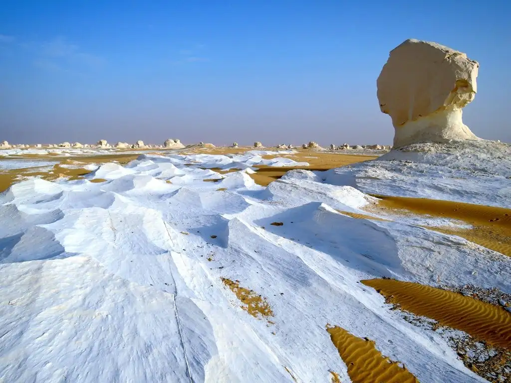 Große weiße Felsformation neben Sand, der wie Schnee aussieht
