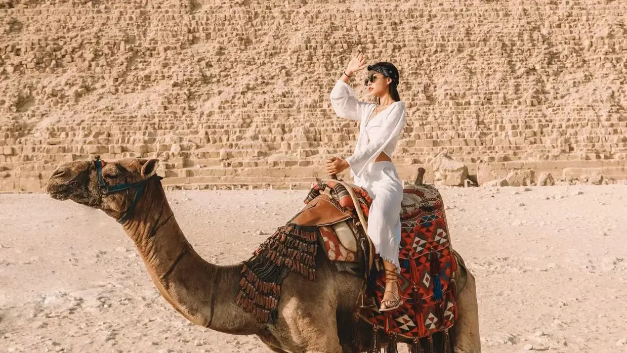 Traveler riding a camel near the Pyramids of Giza, Egypt