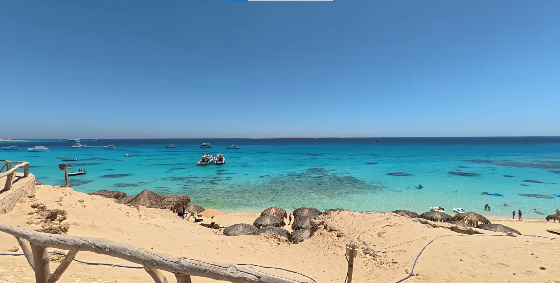 Türkisfarbenes Wasser und weißer Sandstrand der Mahmya-Insel Hurghada mit Booten und Strohschirmen