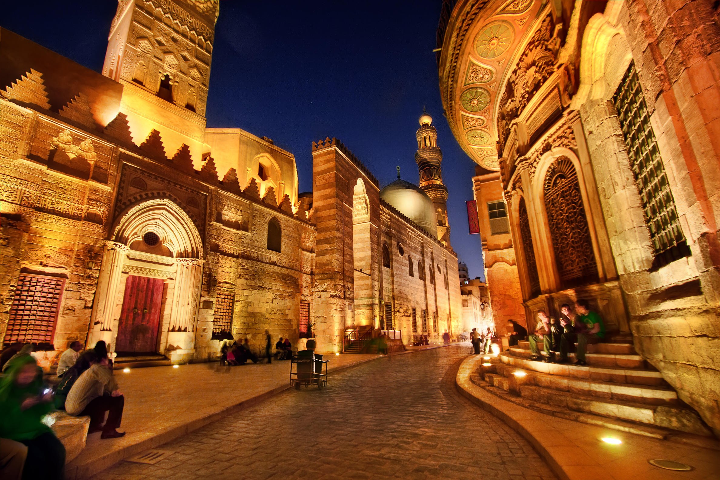 Night view of Al Muizz Street in Islamic Cairo with illuminated historic mosques and monuments