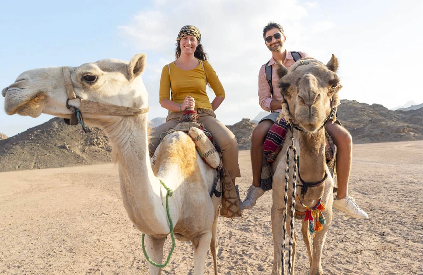 honeymooning couple riding camels in egypt desert safari