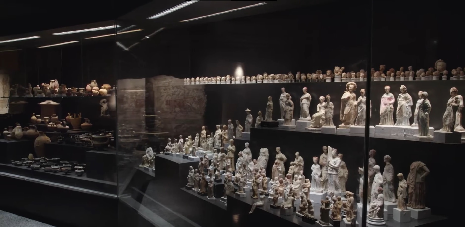 Reihen antiker Statuen in einer schwach beleuchteten Galerie des Museums